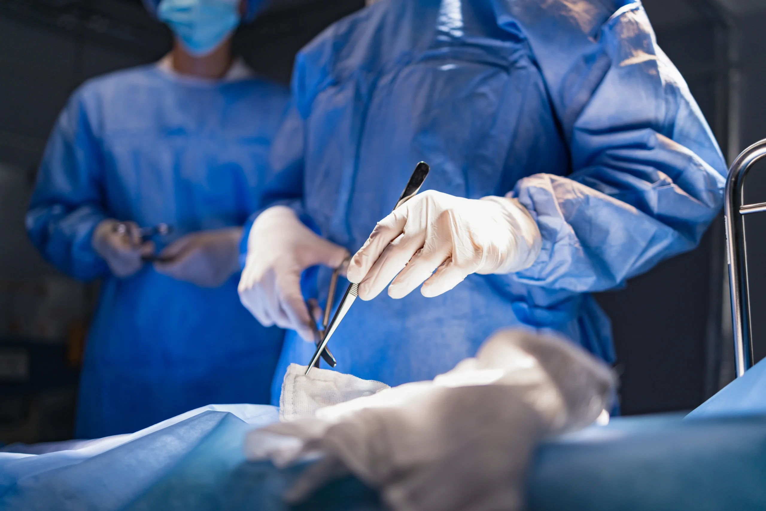 Surgical team operating, with gloved hands and instruments in view